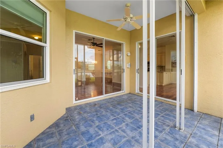 Outdoor patio featuring blue tile flooring, a ceiling fan, and multiple sliding glass doors