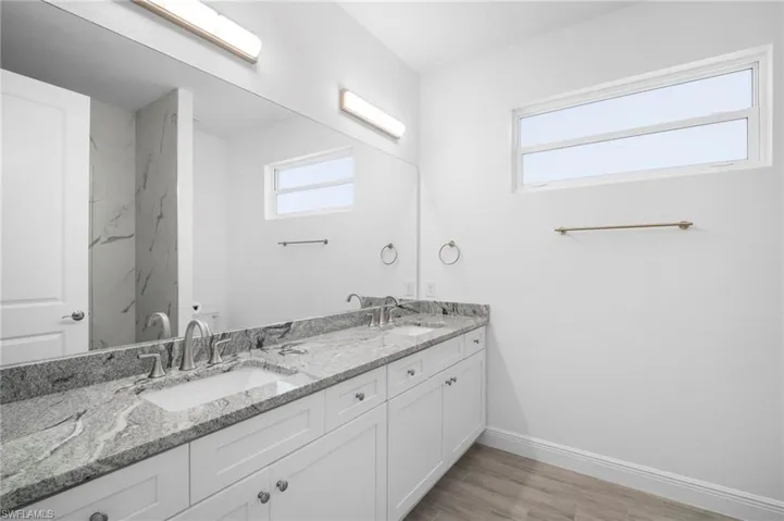 Bathroom featuring double vanity and light wood-style flooring