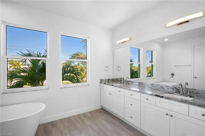 Full bathroom featuring a freestanding tub, double vanity, and light wood finished floors