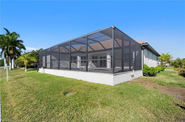 Back of property with a sunroom, a yard, glass enclosure, and a swimming pool