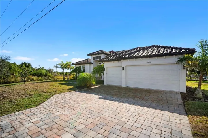 View of front of property with decorative driveway, a front lawn, stucco siding, an attached garage, and a tiled roof