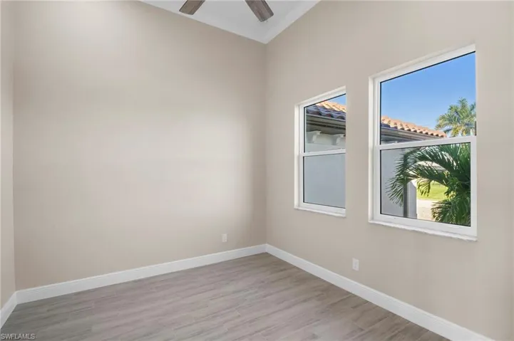 Spare room with light wood-style floors, crown molding, and a ceiling fan