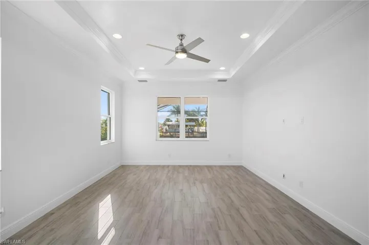 Unfurnished room featuring light wood-style flooring, recessed lighting, crown molding, a ceiling fan, and a raised ceiling