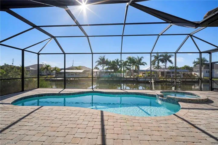 View of swimming pool with a sunroom, a pool with connected hot tub, glass enclosure, a water view, and a residential view