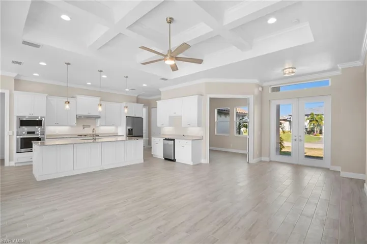Kitchen with coffered ceiling, ornamental molding, pendant lighting, white cabinets, and beamed ceiling