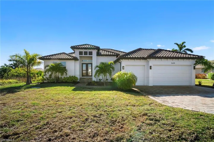 View of front of home featuring stucco siding, a front yard, french doors, and decorative driveway