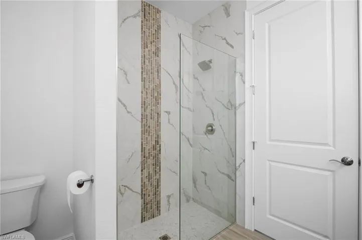 Full bathroom featuring a marble finish shower and toilet
