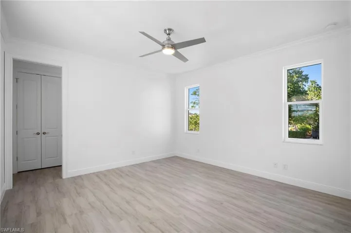 Empty room with crown molding, light wood-type flooring, and ceiling fan