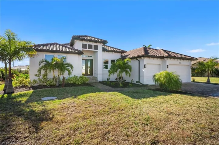 Mediterranean / spanish home with an attached garage, stucco siding, a front yard, and french doors