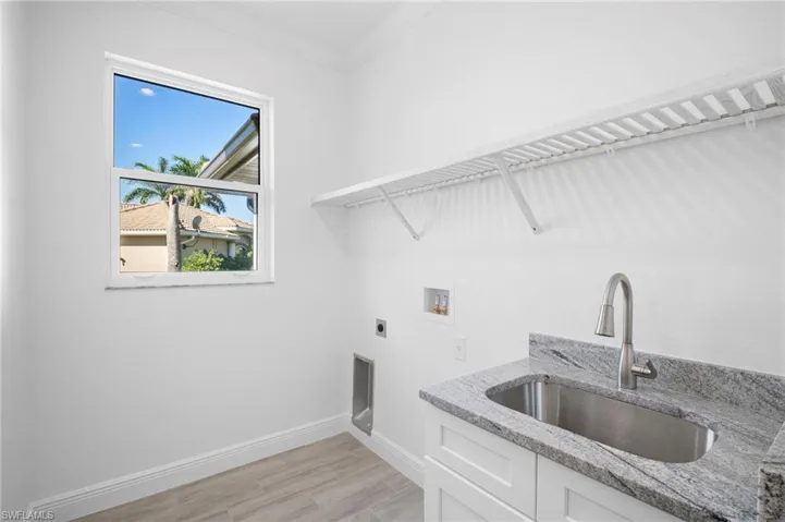 Laundry area with hookup for an electric dryer, washer hookup, wood tiled floors, crown molding, and cabinet space