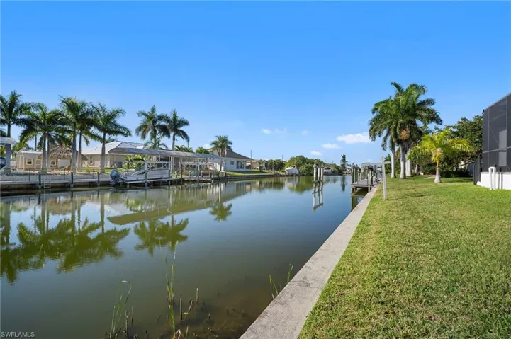 Dock area with a water view, a lawn, and a residential view