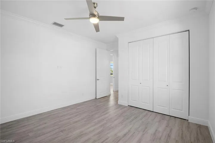 Unfurnished bedroom featuring ornamental molding, wood finished floors, a ceiling fan, and a closet