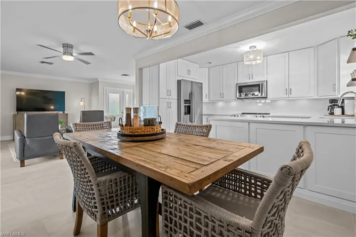 Dining space featuring crown molding, light tile patterned floors, a chandelier, and a ceiling fan
