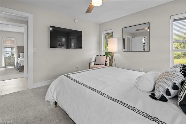 Tiled bedroom featuring multiple windows, carpet flooring, and a ceiling fan