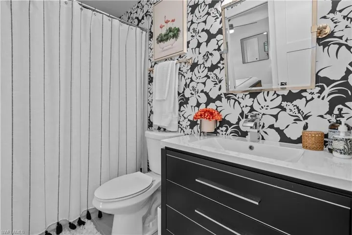 Full bath with vanity, wallpapered walls, and a shower with curtain