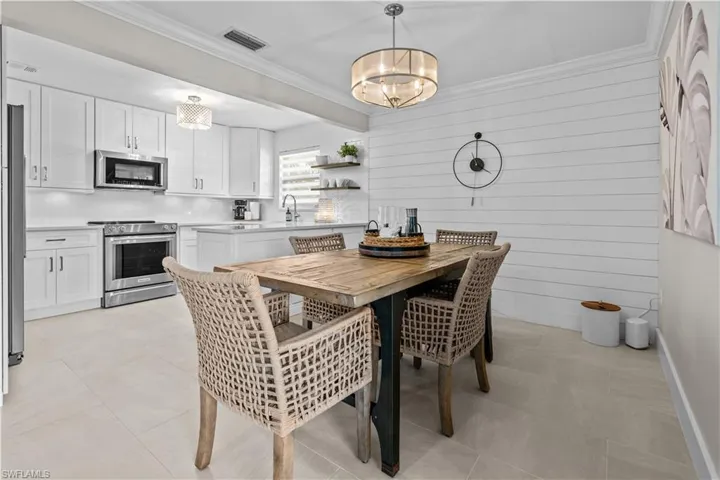 Dining space featuring crown molding, wood walls, light tile patterned floors, and a chandelier