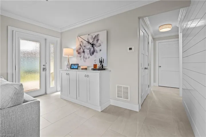 Hallway featuring ornamental molding and light tile patterned floors
