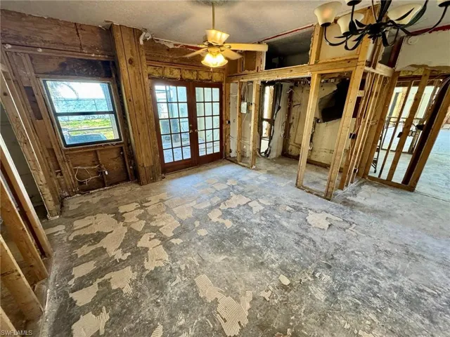 Misc room featuring ceiling fan with notable chandelier and french doors