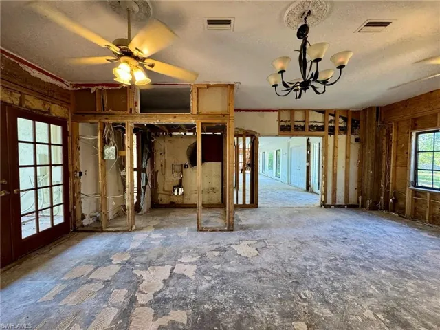Unfurnished bedroom with french doors, a textured ceiling, and a chandelier