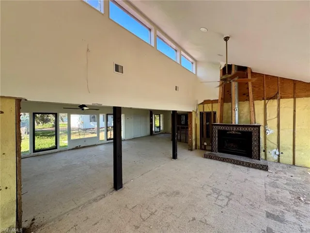 Unfurnished living room with ceiling fan, plenty of natural light, and a high ceiling