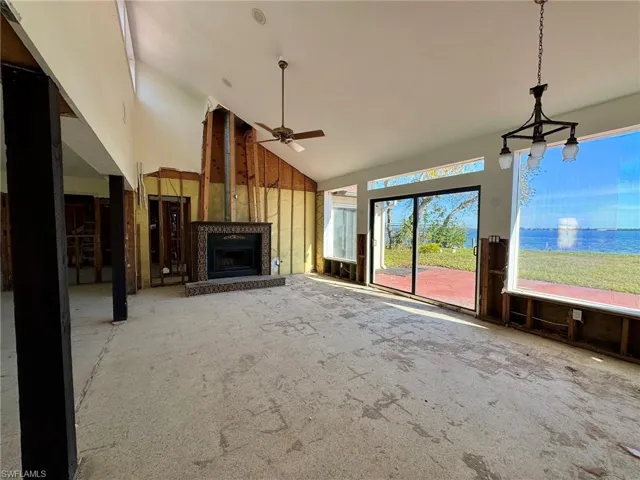 Unfurnished living room with carpet floors, ceiling fan, a water view, and high vaulted ceiling