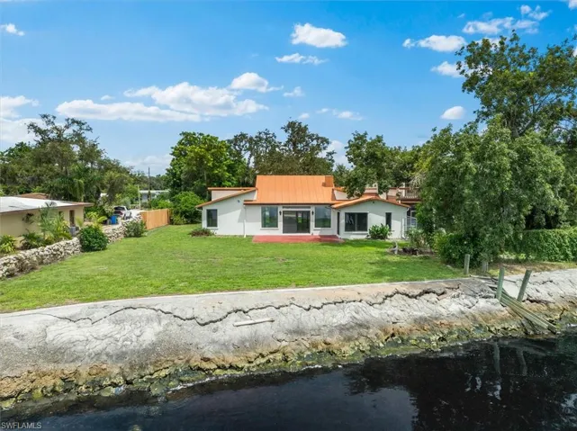 Rear view of house with a yard and a water view