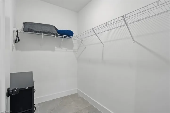 Spacious closet featuring light marble finish floors