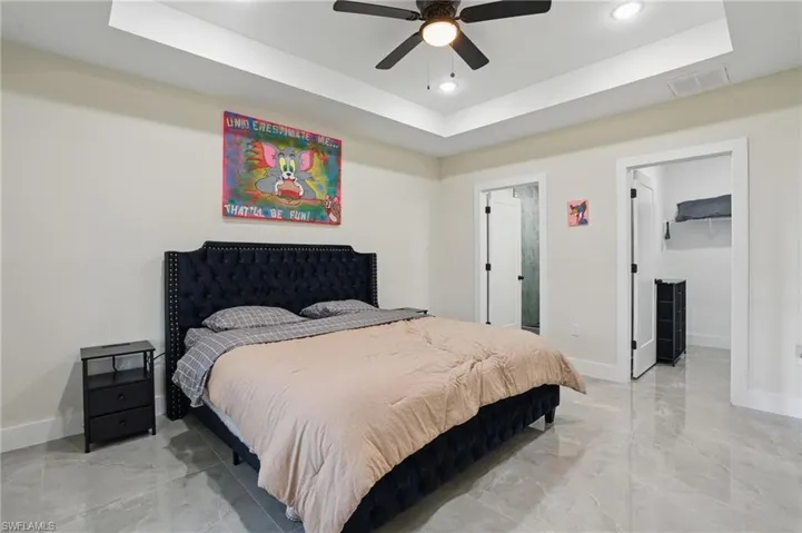 Bedroom with a tray ceiling, baseboards, light marble finish flooring, and recessed lighting