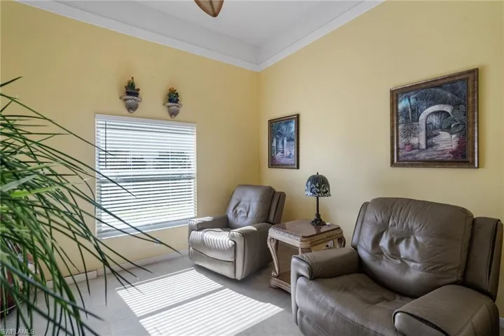 Living area featuring carpet floors, ceiling fan, and crown molding
