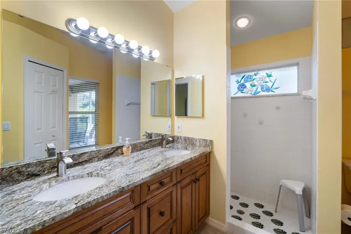 Bathroom with tiled shower, vanity, and tile patterned floors