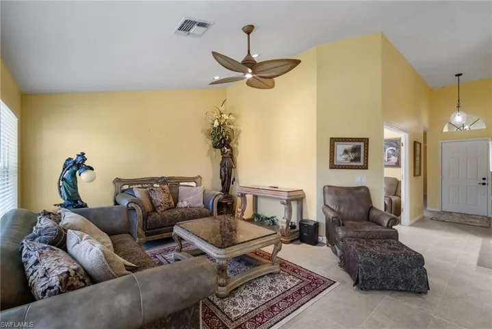 Living room featuring ceiling fan, light tile patterned floors, and vaulted ceiling
