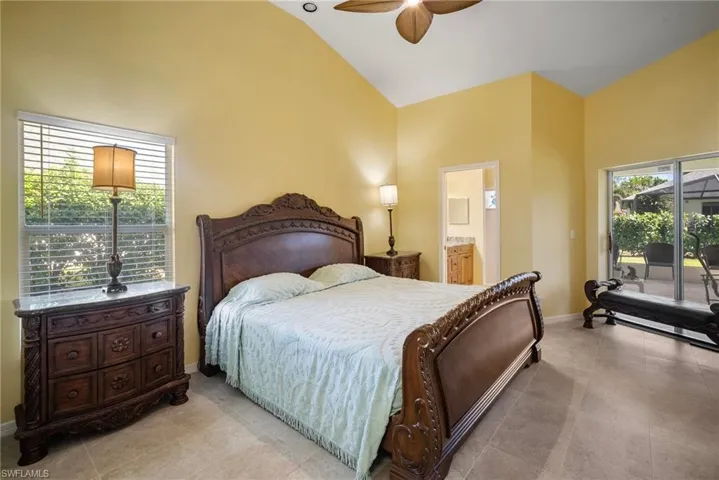 Bedroom with access to outside, ceiling fan, high vaulted ceiling, and ensuite bathroom