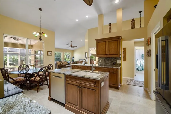 Kitchen featuring appliances with stainless steel finishes, backsplash, ceiling fan with notable chandelier, sink, and pendant lighting