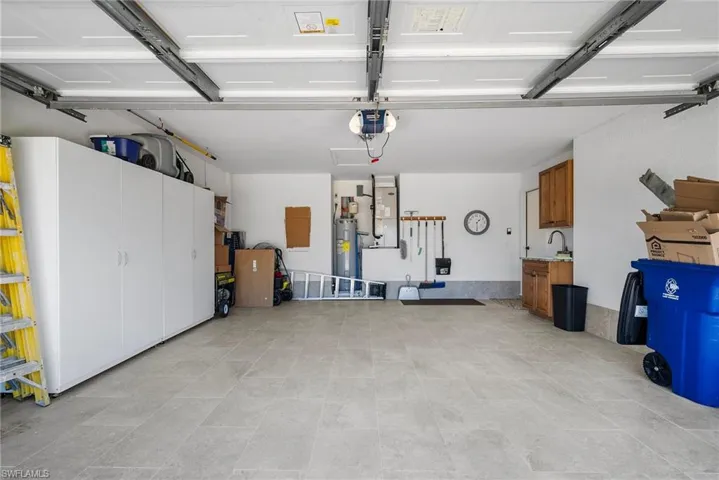 Garage featuring electric water heater and a garage door opener