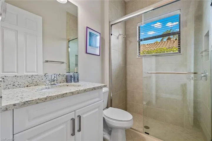 Bathroom with tile floors, vanity with extensive cabinet space, an enclosed shower, and toilet