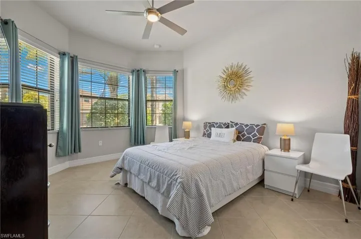 Tiled bedroom featuring ceiling fan and multiple windows
