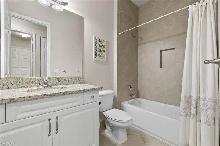 Full bathroom with tile flooring, shower / tub combo with curtain, toilet, and vanity