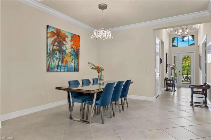 Tiled dining area featuring a notable chandelier, ornamental molding, and french doors