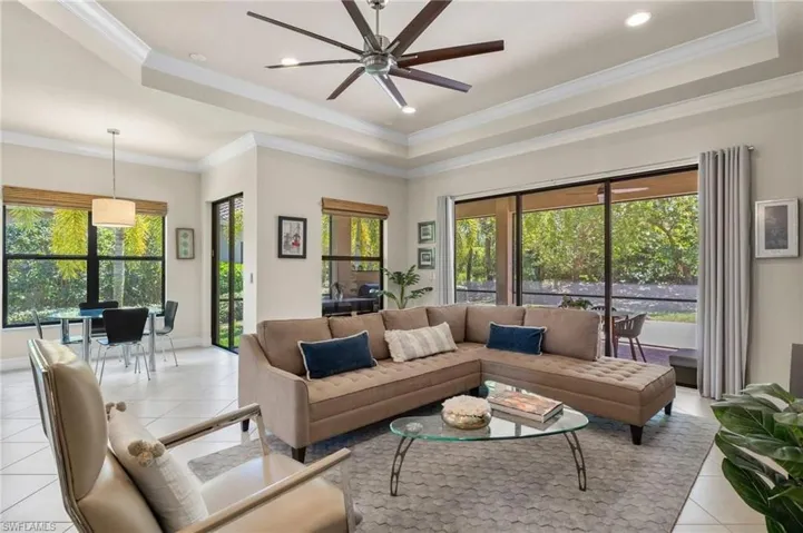 Tiled living room with a tray ceiling, crown molding, and ceiling fan