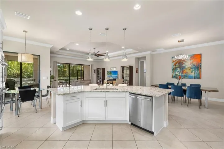 Kitchen featuring stainless steel dishwasher, white cabinets, decorative light fixtures, ceiling fan, and a raised ceiling