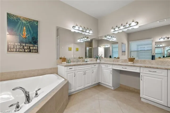 Bathroom featuring tile flooring, tiled tub, and vanity with extensive cabinet space