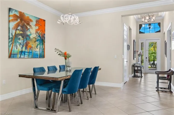 Tiled dining room featuring a notable chandelier, a high ceiling, and crown molding