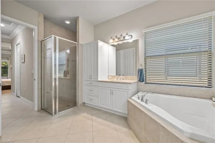 Bathroom with tile flooring, vanity, crown molding, and plus walk in shower