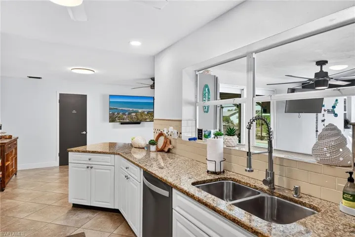 Kitchen with a ceiling fan, white cabinets, light stone countertops, stainless steel dishwasher, and recessed lighting