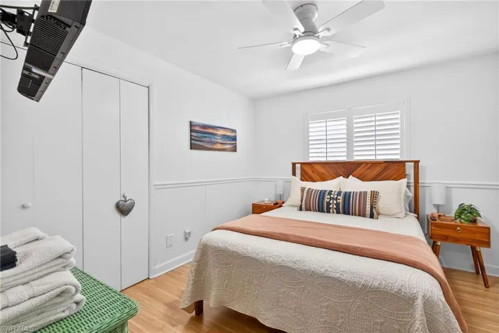 Bedroom featuring light wood-style flooring, a closet, wainscoting, and a ceiling fan