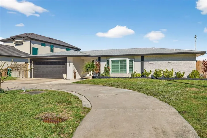 View of front of house with driveway, brick siding, stucco siding, and an attached garage