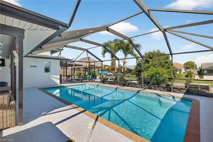 Swimming pool featuring a patio area, a sunroom, and glass enclosure