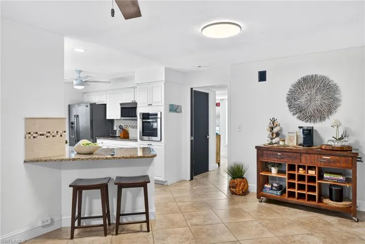 Kitchen with a kitchen breakfast bar, tasteful backsplash, white cabinets, a peninsula, and ceiling fan