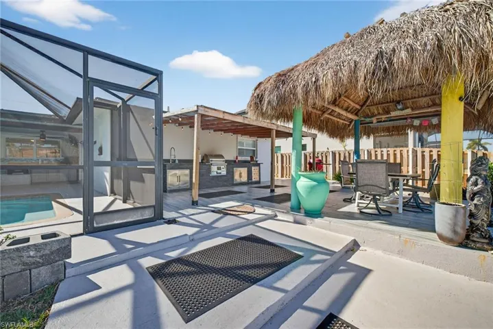 View of patio with an outdoor kitchen / dining area, glass enclosure, and a wooden deck