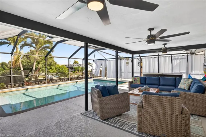 Swimming pool featuring a sunroom, an outdoor living space, glass enclosure, and a patio